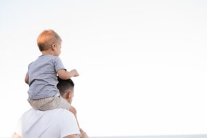 Ein Mann hält einen Jungen auf seinen Schultern und demonstriert damit die endlosen Fähigkeiten der Eltern.
