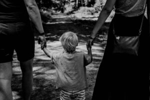 Ein Schwarz-Weiß-Foto einer Familie, die Händchen haltend auf einem Weg unterwegs ist und zeigt, wie Eltern ihre Kinder auf das Leben vorbereiten können.