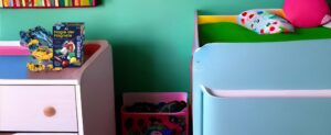 Ein Kinderzimmer mit Bett und Kommode, gefüllt mit Spielzeug (Spielzeug) für Kinder ab 9 Jahren.