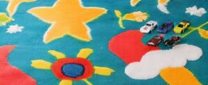 Ein farbenfroher Teppich mit Spielzeugautos und Sternen darauf.