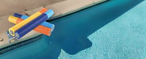 Eine Luftaufnahme eines Schwimmbades mit bunten „Wasserspritzen“-Schwimmkörpern.